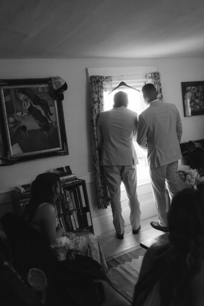 Groomsmen looking out the window waiting for the rain to pass 