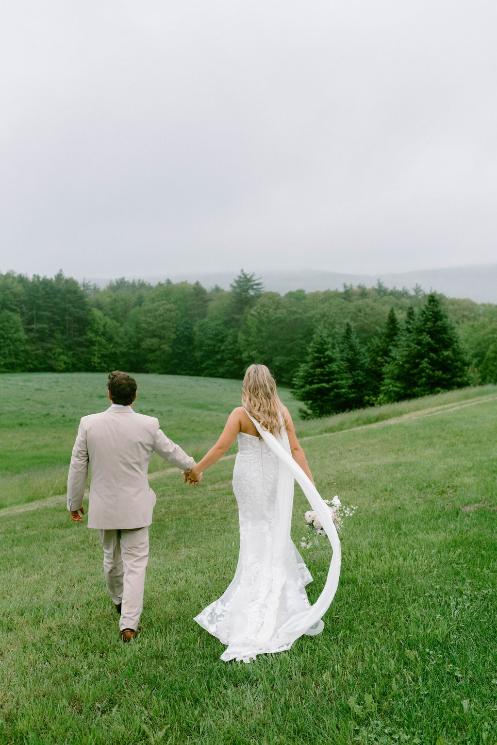 Bride & Groom walkng and holding hands looking at the mountains in NH Saddle Hill Farm wedding