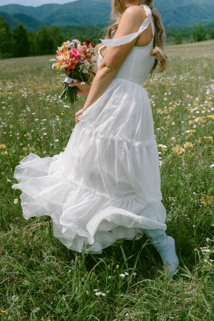 Your Dream Guide to a Smoky Mountain Elopement Bride & Groom in a field of wildflowers Blue cowgirl boots