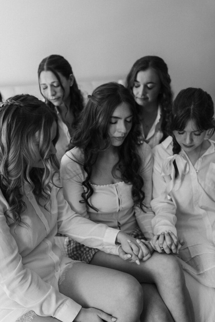 black and white picture of the bride and bridesmaids praying while getting ready before her romantic wedding day
