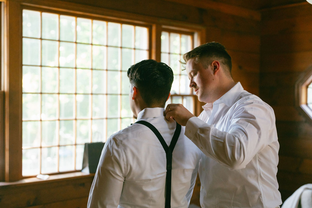 a groomsmen helping the groom get ready
