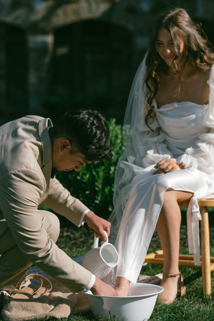 Groom washing his bride's feet during wedding ceremony