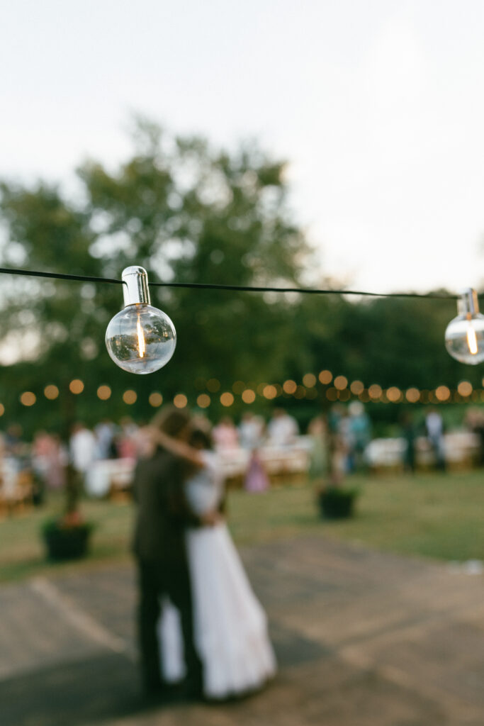 bride and groom dancing with string lights at reception