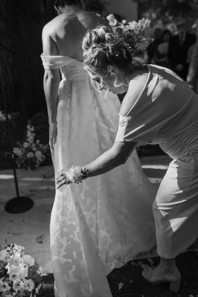 mom straightening dress for bride after walking down aisle 