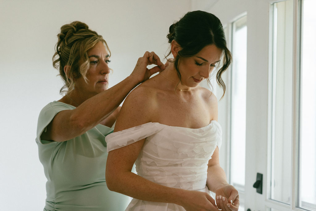 mother of the bride helping her with her necklace