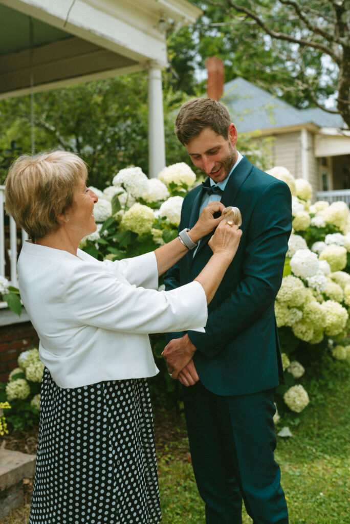mother of the groom helping him with his tie