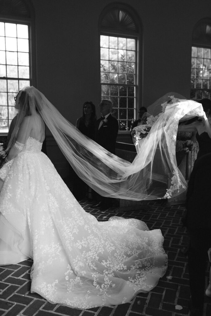 sister of the bride helping her with her veil 
