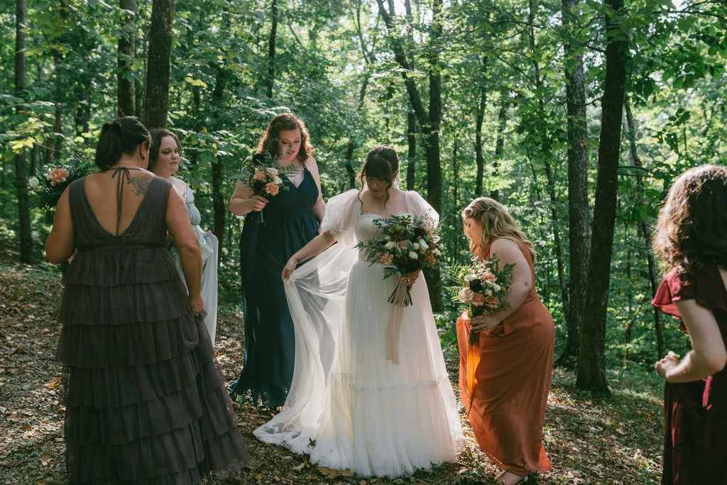 picture of the bridesmaids helping the bride with the dress for her portrait 