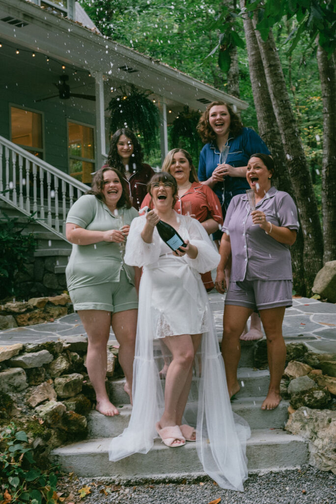 bride and her bridesmaids with a bottle of champagne 