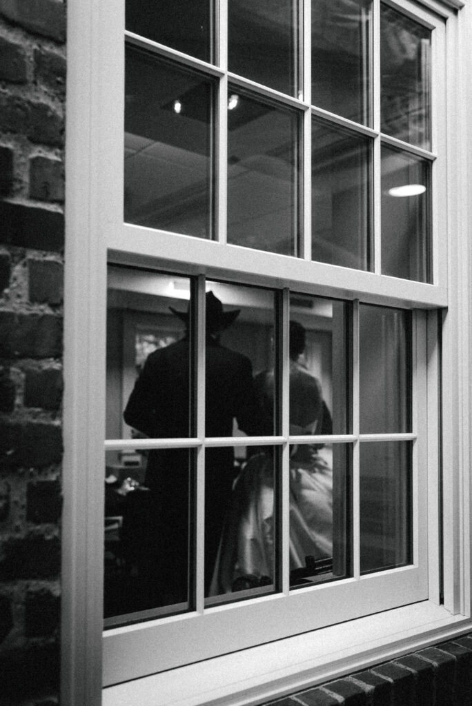 Bride & groom through the window in black and white