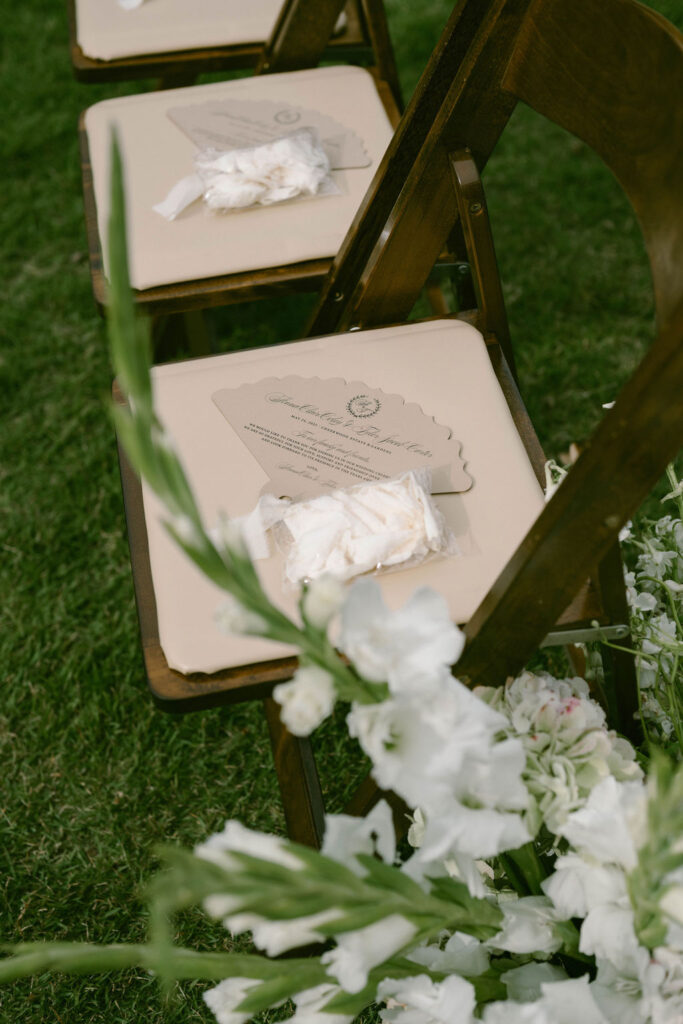 Custom fans for ceremony guests on chairs with flower petals 