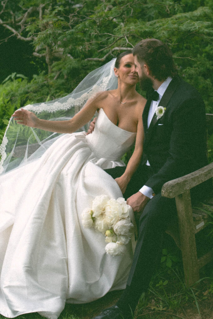 Bride & groom sitting on a bench surrounding by the gardens at Cheekwood Estate