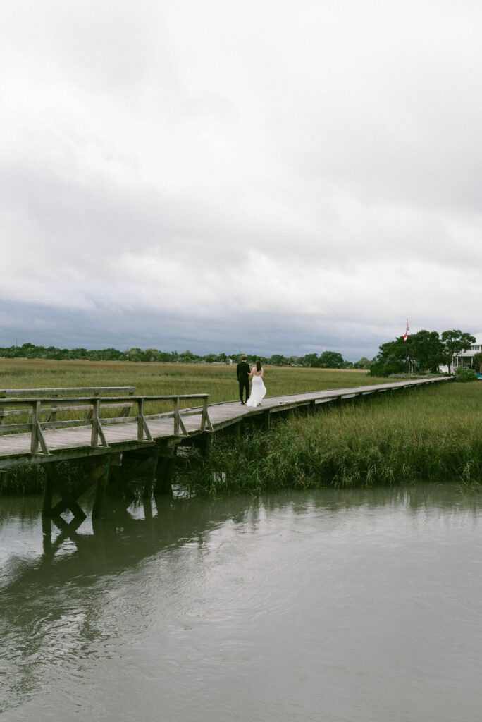Bride & Groom walking on dock over marsh after getting married