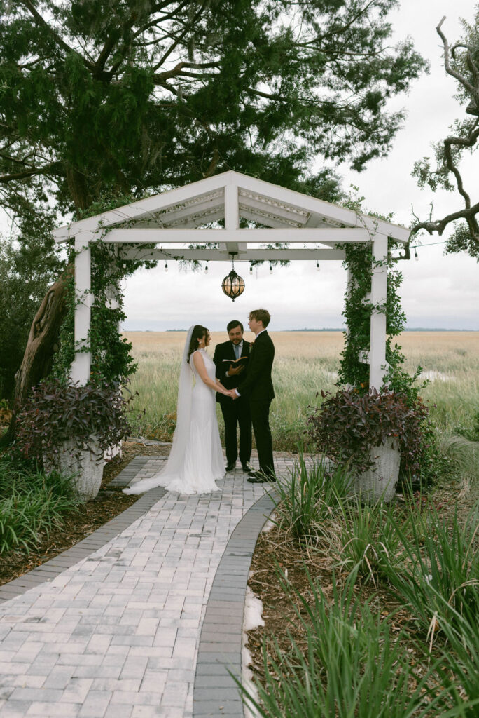 bride & groom standing under ceremony arch at The Venue on Tybee