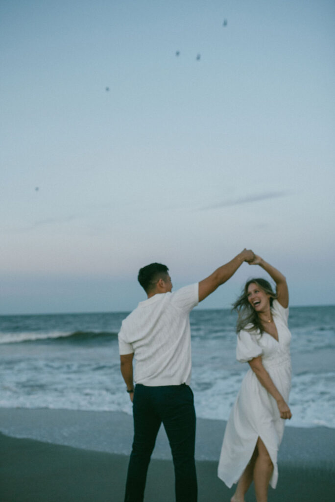 cute couple dancing at tybee island, GA at their cozy beach engagement session 