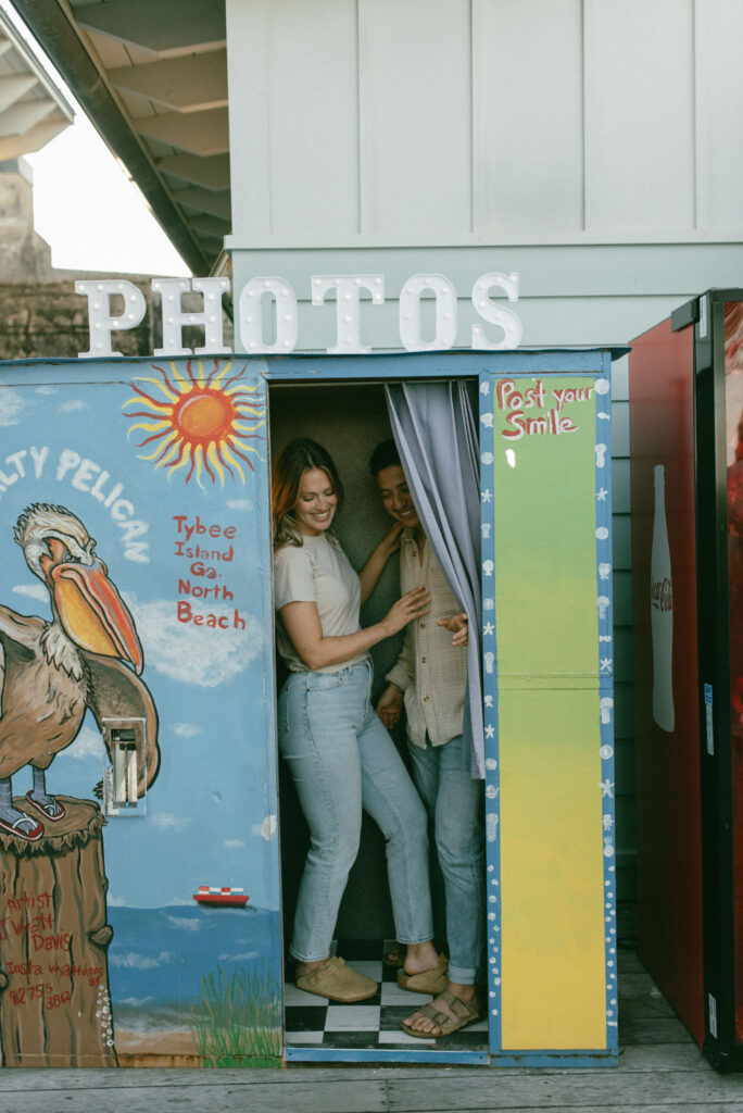 couple at a photo booth during their cozy beach engagement session 