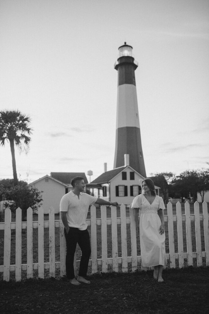 couple holding hands with the lighthouse in the background 