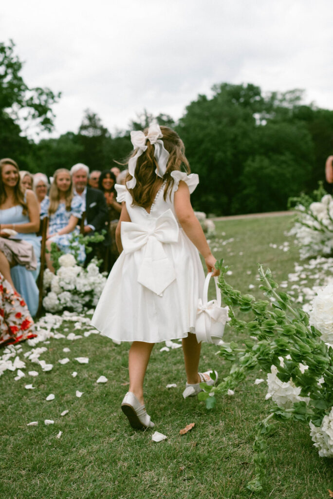 FLower girl running back down the aisle with flower petals on the grpund