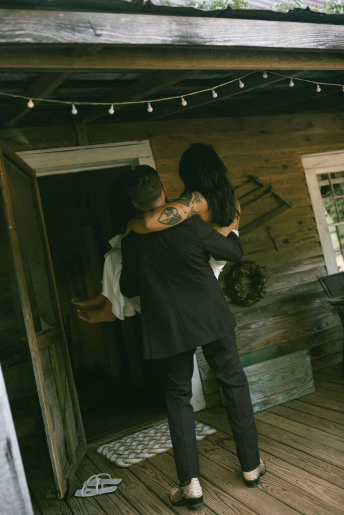 Groom caring his bride through the threshold Country cabin