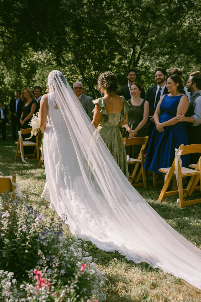 bride & mom walking down the aisle at a jane austen inspired intimate backyard wedding