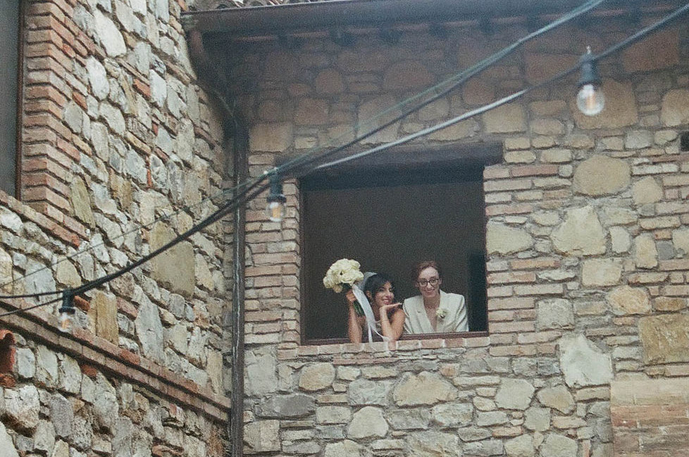 an intimate Italian escape Brides leaning out window with bouquet 35mm film 
